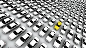One yellow lemon car standing out among a lineup of white vehicles — NC lemon law attorney representing defective vehicle owners